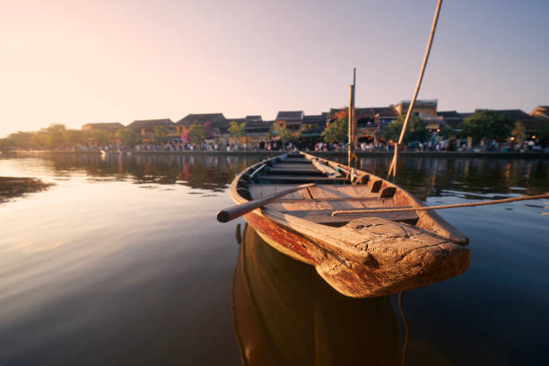 Close-up wooden boat moored in ancient city Hoi An Close-up wooden boat moored against busy waterfront ancient city Hoi An at sunset. Popular tourist destination in Vietnam. thu bon river stock pictures, royalty-free photos & images