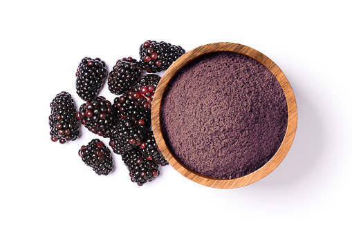 Blackberry powder in wooden bowl and fresh blackberries isolated on white background, top view, flat lay.