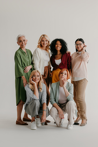 Grupo multiétnico de mujeres maduras que se unen y sonríen sobre un fondo gris photo