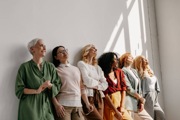 Multi-ethnic group of mature women bonding and smiling while leaning on the wall together