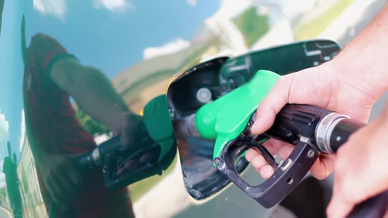 Petrol Station Attendant Removing Delivery Nozzle from the Car Fuel Tank.