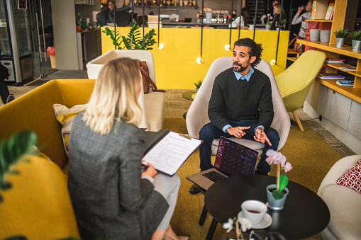 Cheerful Middle Eastern businessman meeting a Caucasian businesswoman in a cafe. Drinking coffee and having a discussion.