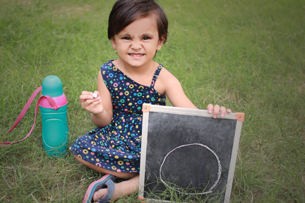 niña alegre mostrando un gran cero en la pizarra - bebes 0 1 fotografías e imágenes de stock