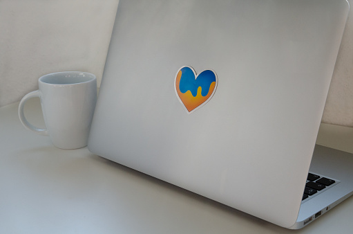Close up on an open laptop with a blue and yellow heart shape sticker