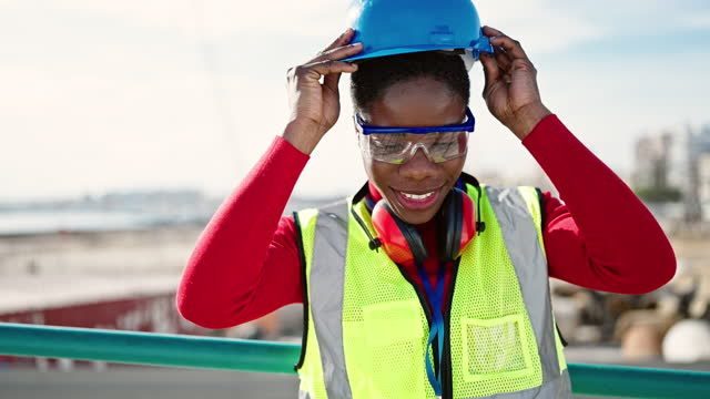 African american woman architect smiling confident wearing hardhat at street