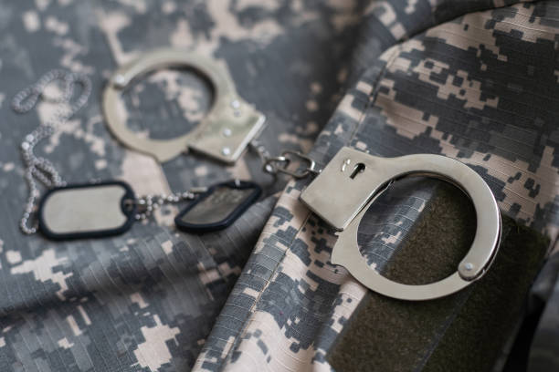 istock military camouflage uniform, handcuffed on background. 1492278154
