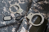 military camouflage uniform, handcuffed on background.