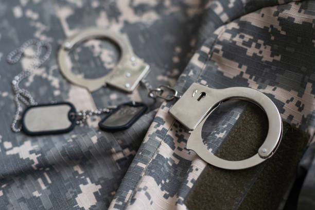 military camouflage uniform, handcuffed on background. - war criminal imagens e fotografias de stock