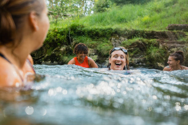 Joyful River Swim Group of women wild swimming in the Lake District, North West of England. They are in a river, enjoying time outdoors. woman cold water swimming stock pictures, royalty-free photos & images