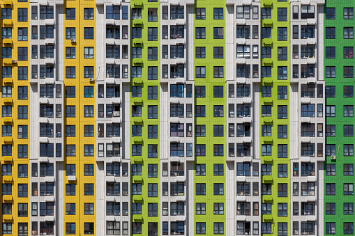 Multi-colored wall of an apartment building with the same type of windows and balconies.