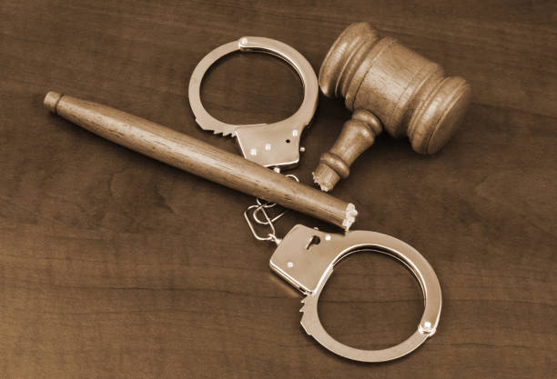 istock Handcuffs and broken wooden gavel on table. 1492278886