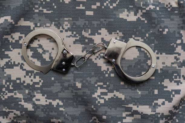 istock military camouflage uniform, handcuffed on background. 1492279932