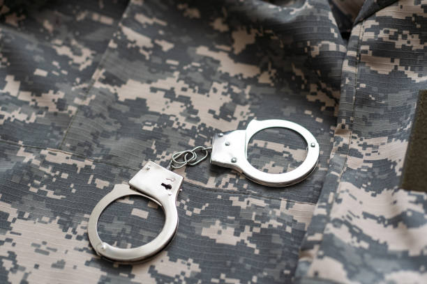 istock military camouflage uniform, handcuffed on background. 1492282340