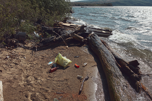 Collected trash thrown away on a river shore.