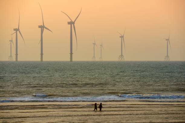 istock Fans of wind turbines spin over the sparkling sea. Dynamic clouds at sunset. 1492283057