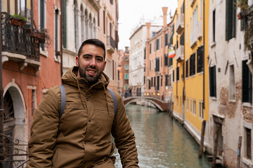 Young male tourist on the canals of Venice happily