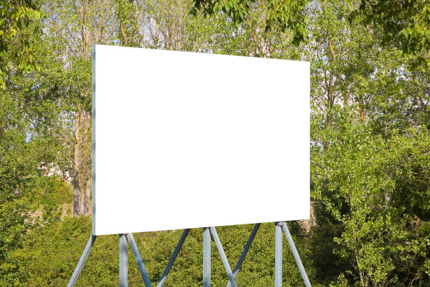 istock Blank advertising signboard with trees on background - concept with copy space for text inserting 1492284818