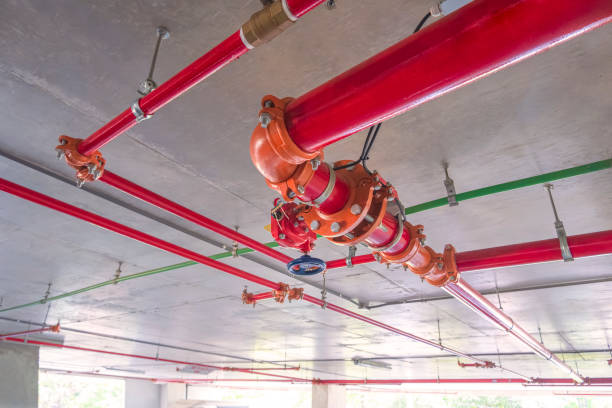Red fire protective water pipeline system on concrete ceiling inside of parking garage building