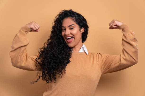 istock fun woman flexing arms in beige studio 1492288817