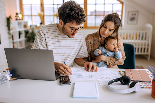 Familia joven con un lindo bebé que repasa las finanzas en casa photo