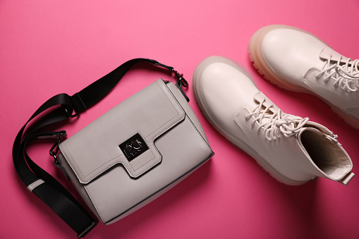 Pair of stylish leather shoes and bag on pink background, flat lay