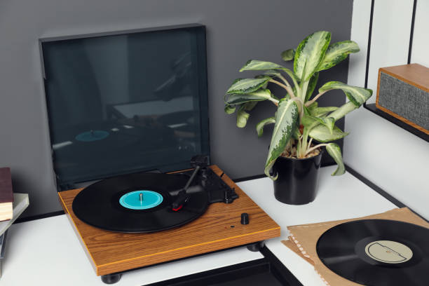 istock Stylish turntable with vinyl disc near grey wall in room 1492291679