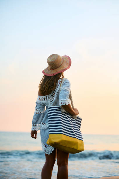istock Back view of woman with sun hat walking on the beach. 1492295521