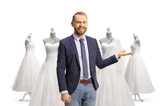 Young professional man pointing at bridal gowns isolated on white background