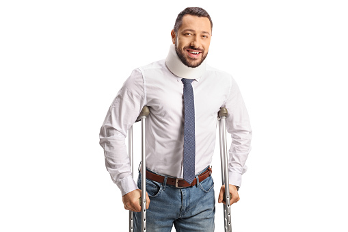 Portrait of an injured man with a cervical collar leaning on crutches isolated on white background