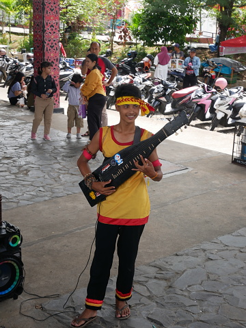 Pontianak, Indonesia - May 21, 2023 - A young man is playing the traditional guitar or sape instrument at the Gawai Dayak event. The festive event welcomes the Gawai Dayak party at the Radakng House