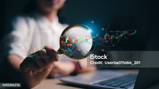 istock Woman hand holding magnifier glass with virtual stock market chart, Business investment earning income concept. stock market for analysis technical grap. 1492304276