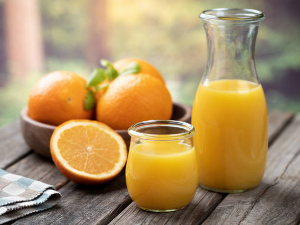 Orange juice in glass and carafe with fresh oranges
