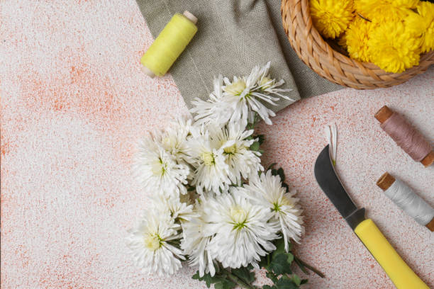 istock Flat lay composition with knife, threads and Chrysanthemum flowers on light textured table, space for text 1492305397