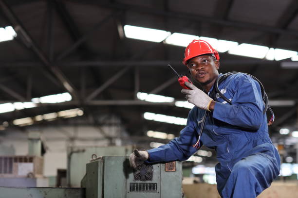 istock Technician engineer or worker man in protective uniform sitting and using walkie talkie radio while controlling work with hardhat and electric cable line at heavy industry manufacturing factory 1492306149