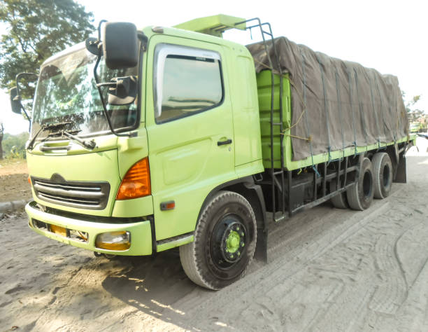 green colored flatbed heavy trucks used to transport and distribute cements sacks from factory to points of sales or distributors networks shops - axel imagens e fotografias de stock