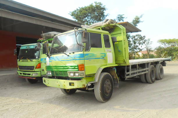 istock Green colored flatbed heavy trucks used to transport and distribute cements sacks from factory to points of sales or distributors networks shops 1492306516