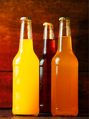 Three glass bottles of lemonade on a wooden table. Summer refreshing drinks
