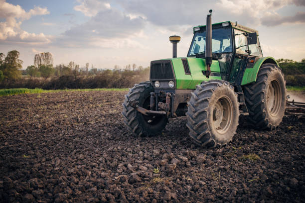 Senior farmer driving a tractor on agricultural field stock photo