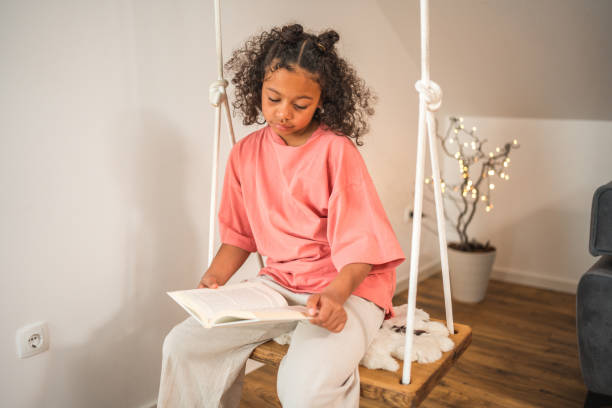 istock Lovely Mixed Race Girl Reading A Book On A Swing 1492313156