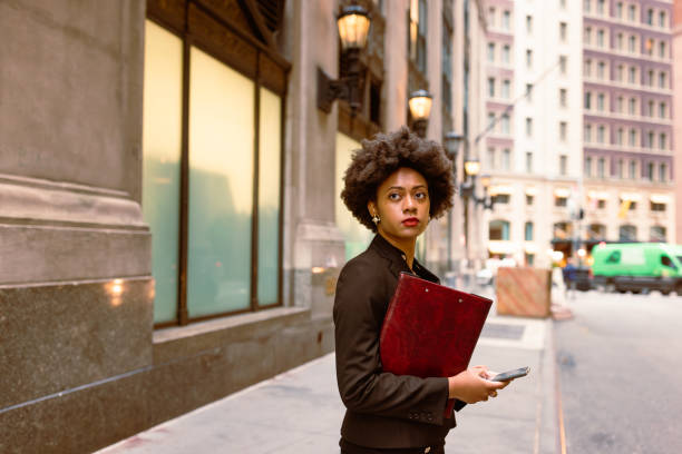 Urban Productivity: Young Black Executive Engaged in Taxi Wait, Handling Documents and Email