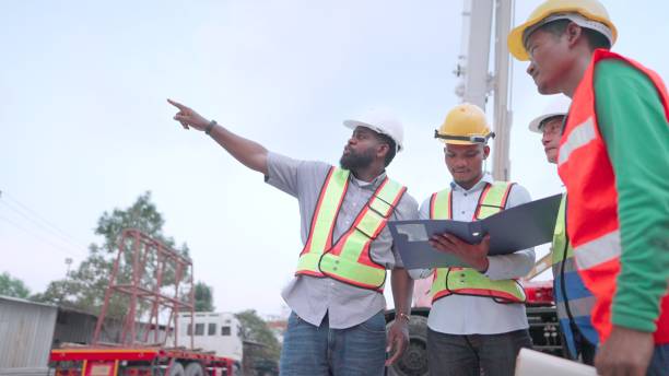 istock Engineer, contractors and partners in construction business together to plan and agreements procedures for the construction of buildings or housing projects. Team contractor in safety uniform working at construction site. Concept of construction business, 1492315407