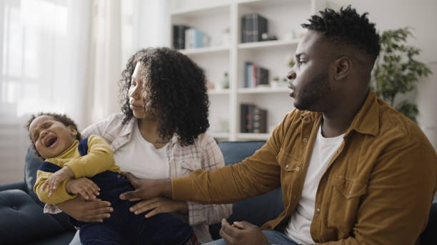 jeunes parents afro-américains essayant de calmer leur fils en bas âge qui pleure, rendez-vous chez le médecin - male nurse nurse doctor group of people photos et images de collection