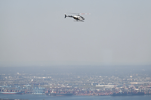 New York, USA, April 13, 2023 - A Bell 206 helicopter operated by New York Helicopter Charter, Inc. (N216MH) flies over the Hudson, Jersey City, New York