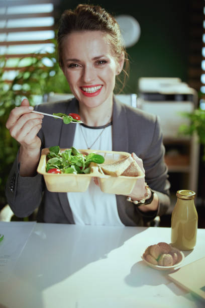 happy modern woman worker in modern green office eating salad