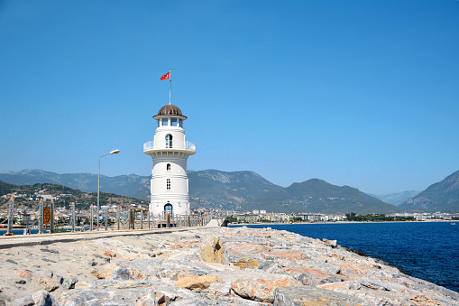 A lighthouse on the shore of the sea with big stones on foreground, copy space