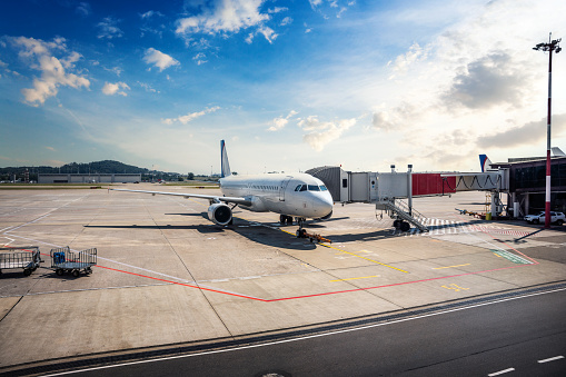 Passenger airplane on the airfield docked with a passenger boarding bridge. Aircraft preparation to departure.