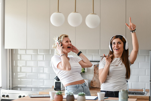 Excited Lesbians Creating Playlist By Voice Recognition While Cooking In Kitchen And Listening To Music