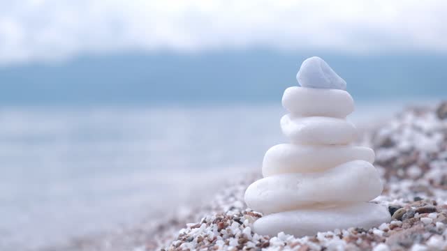 stable pyramidal piles of round stones on pebble beach. serene harmony, calm zen meditation. closeup