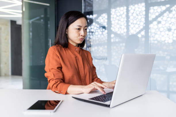 istock Young Asian female programmer, developer, tester is focused and serious sitting in the office and working on a laptop 1492329924