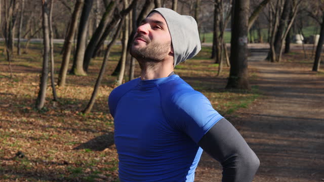 Young man breathing fresh air stretching arms in a park